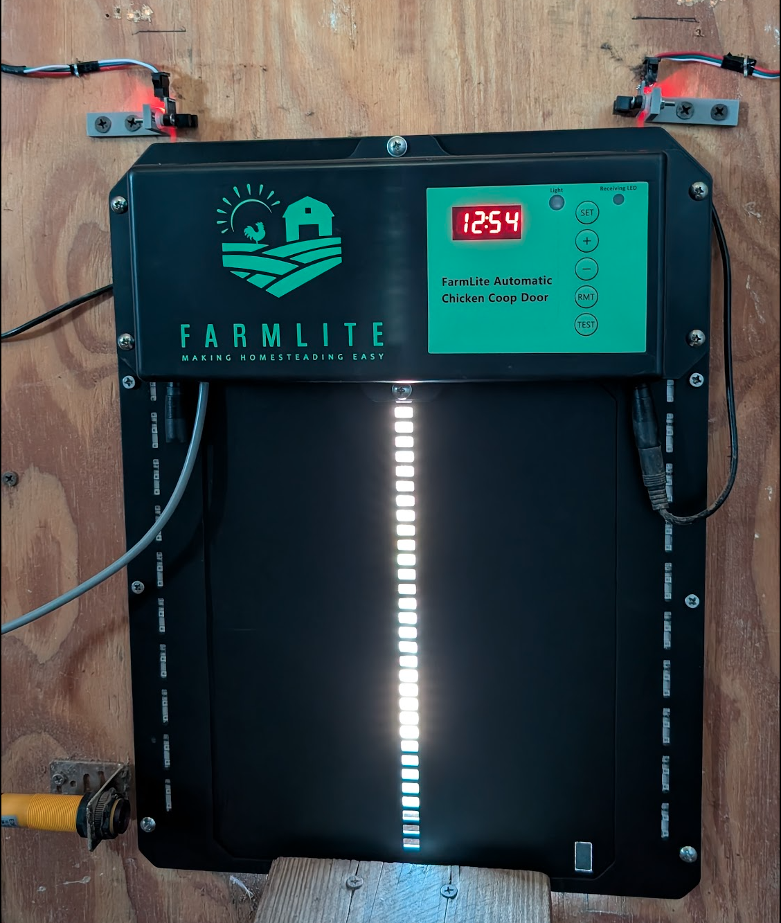 Coop door with sensors mounted above, tracking its open/closed status.